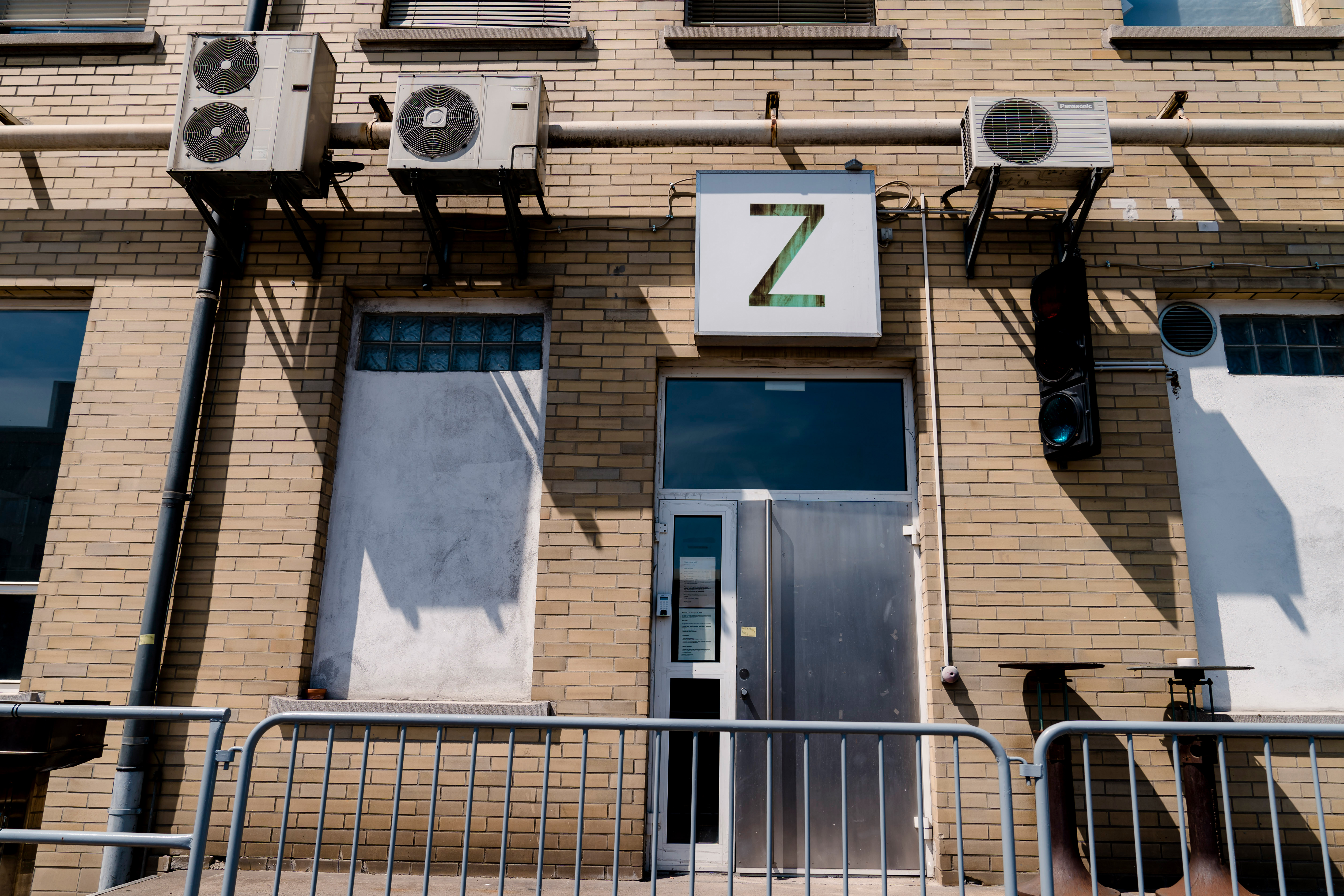 Fassade Schmidtstraße mit Z_Schild Ausschnitt der Fassade eines Industriegebäudes, blinde Fenster, Abluftinstallation Klimaanlagen, Eingangstür mit quadratischen Schild: Grünes Z auf weißem Grund.